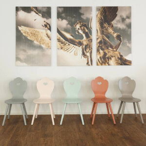 Bunte Herzerlstühle aufgereiht unter Friedensengel