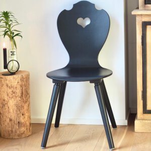 Schwarzer Holzstuhl als moderner Bauernstuhl neben Holzstamm